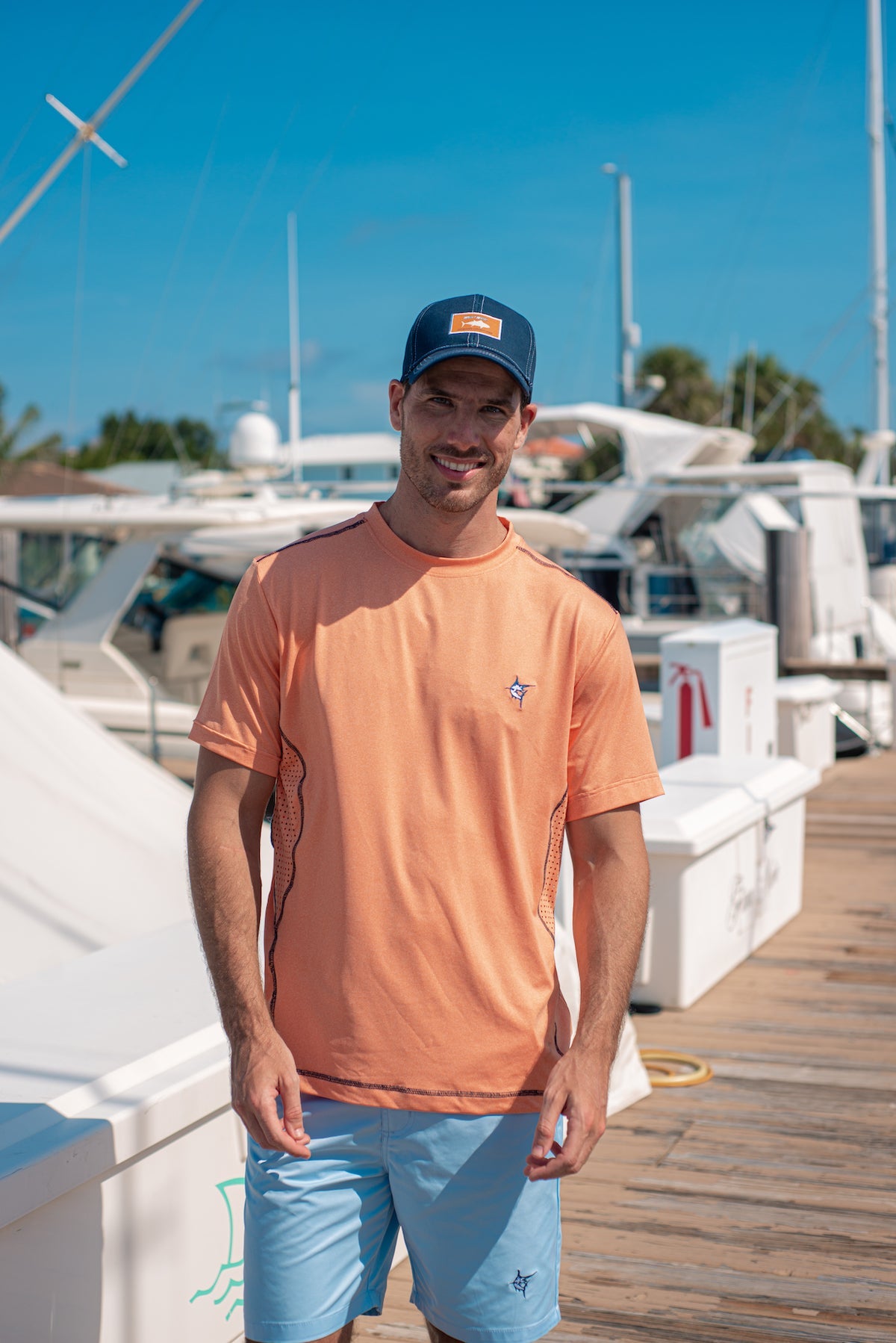 Grander Short Sleeve Performance Tee peach color with White Water Life worn by man at marina on Tampa Home & Garden Store