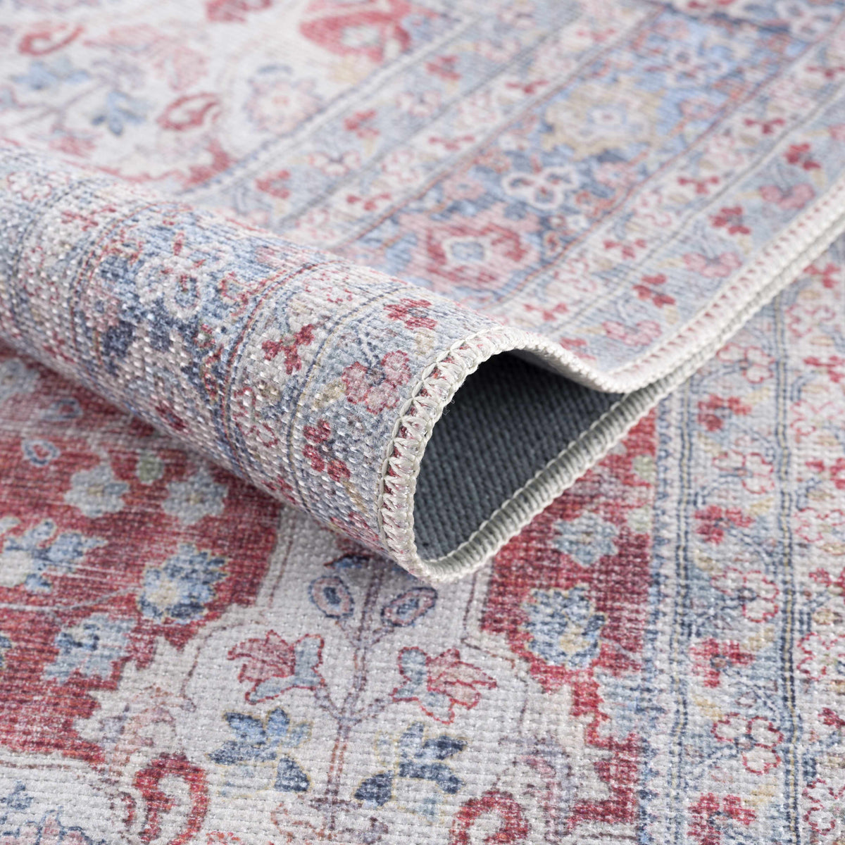 Rust Goma Vintage Area Rug close-up of faded red blue beige pattern with rolled edge on Tampa Home & Garden Store