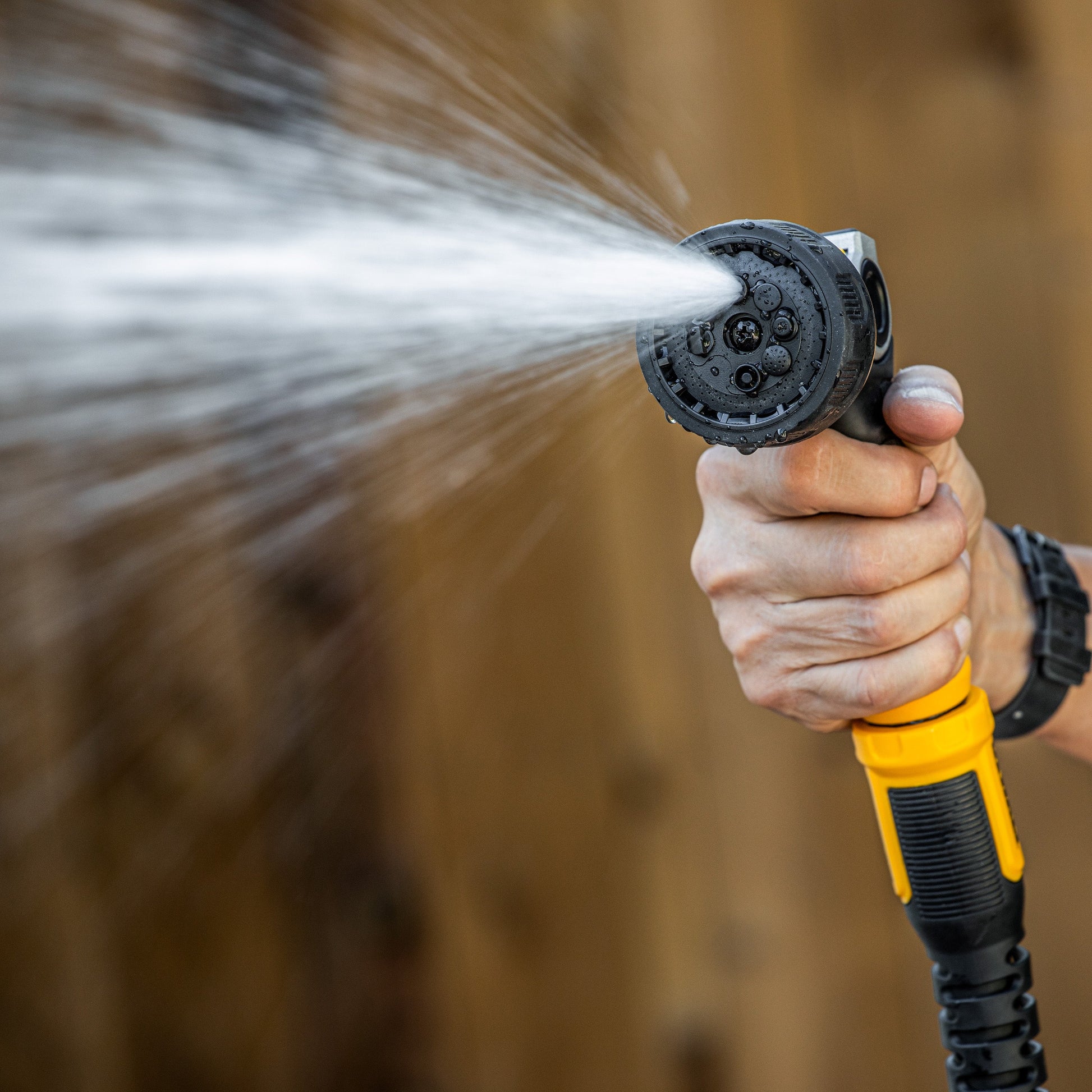 DEWALT Pattern Pro thumb control turret nozzle hose end in black with yellow grip spraying water on Tampa Home & Garden Store