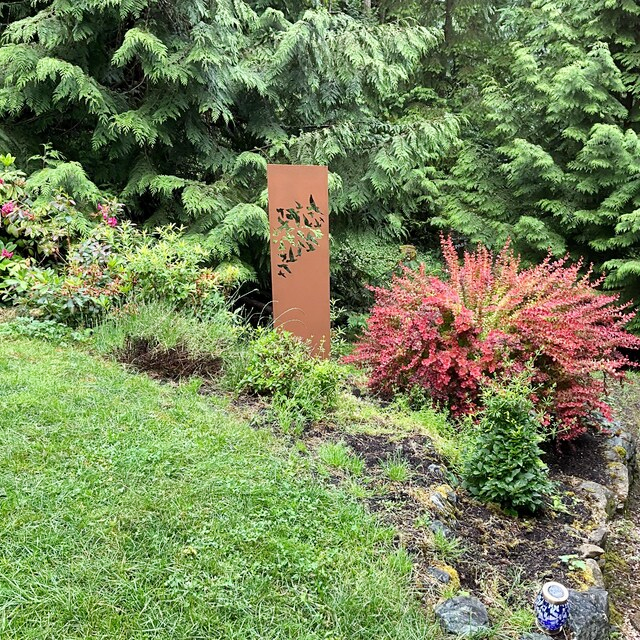 Rustica Ornamentals outdoor screen panel, 46 in rust finish with bird cutouts in a garden bed on Tampa Home & Garden Store