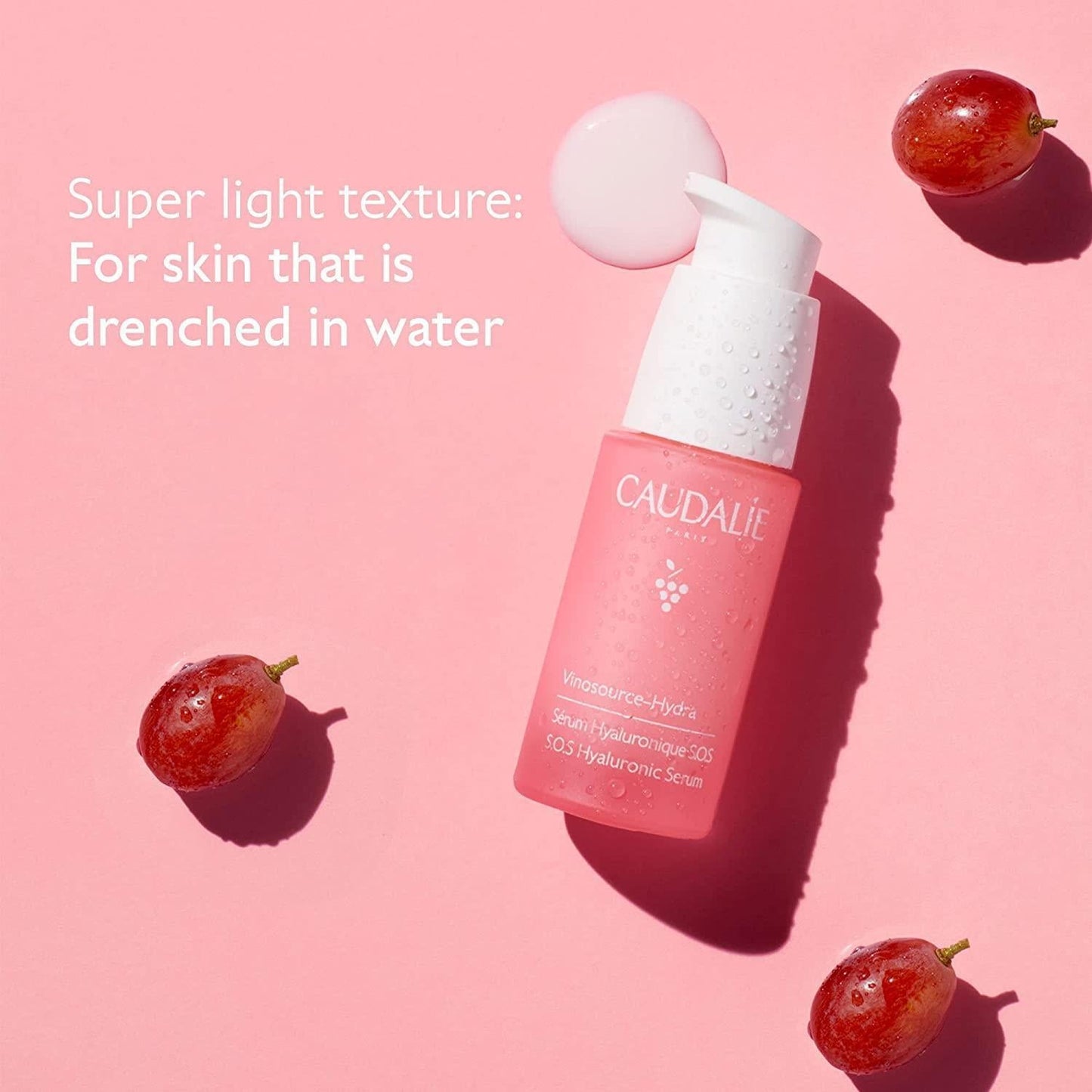 Caudalie Vinosource Hydra SOS Hydrating Serum bottle in pink with white pump beside grapes on Tampa Home & Garden Store