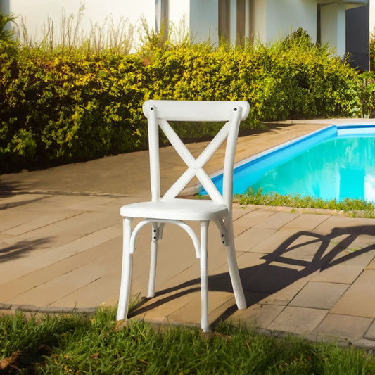 Resin cross-back dining chair, white, outdoor poolside setting with greenery on Tampa Home & Garden Store