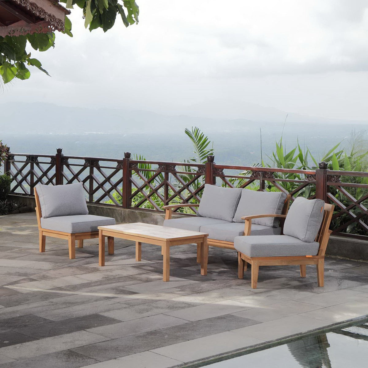 Marina 5-Piece Outdoor Teak Patio Set with gray cushions and two teak coffee tables on a terrace on Tampa Home & Garden Store