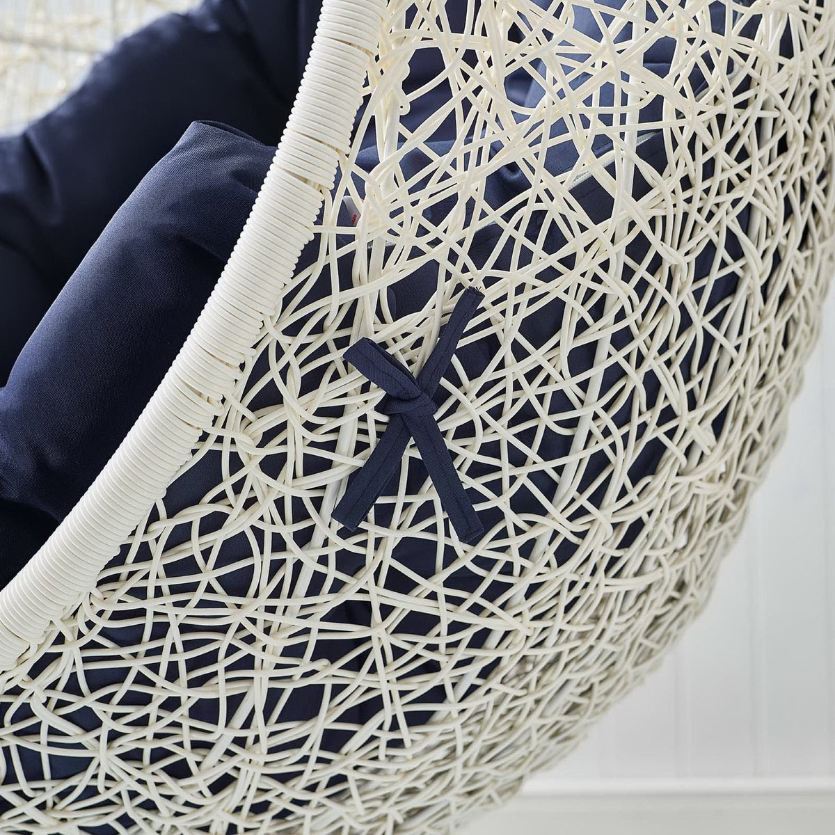 Hide Outdoor Patio Swing Chair With Stand closeup of white wicker frame and navy cushions on Tampa Home & Garden Store