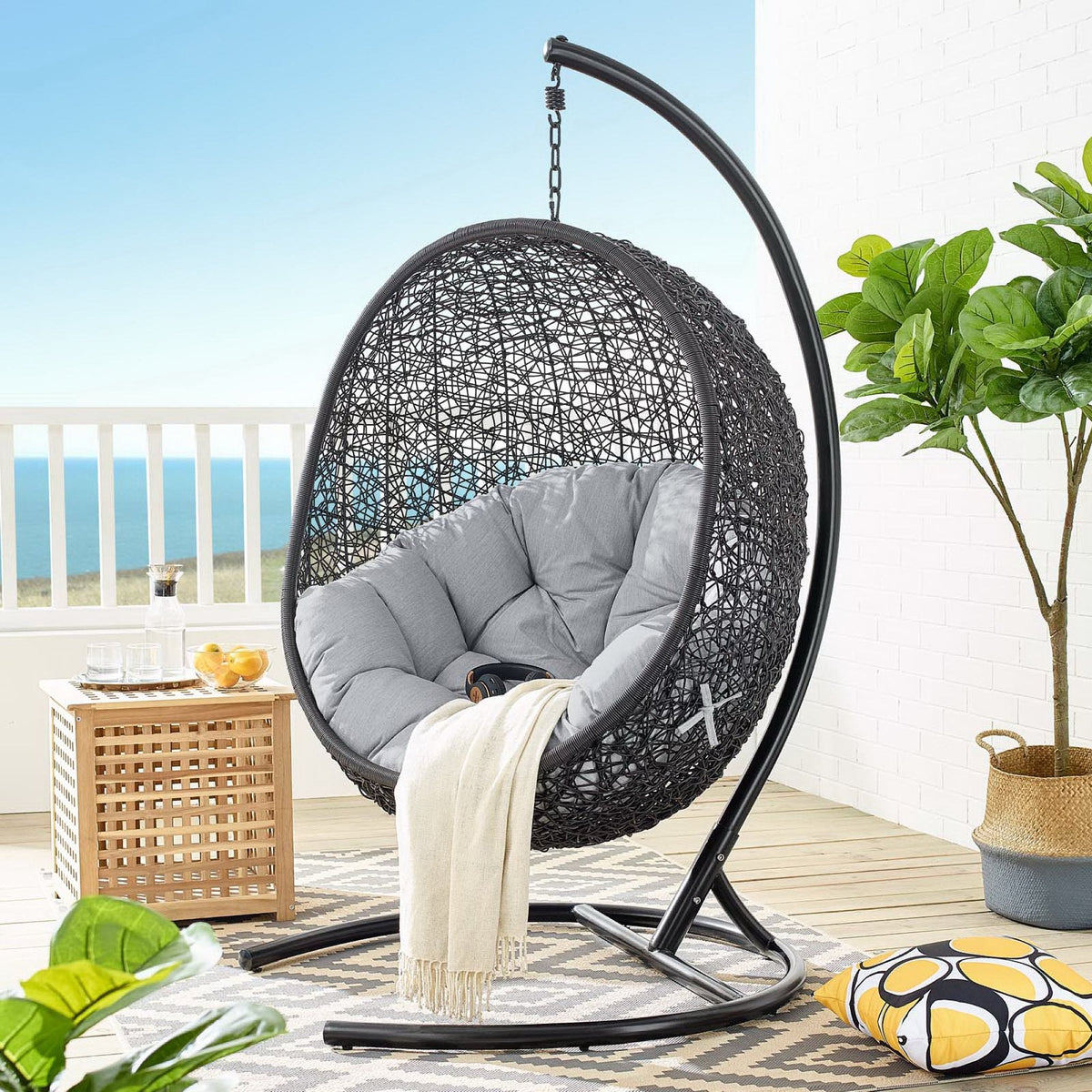 Encase Swing outdoor lounge chair with gray cushions in circular wicker on curved stand on Tampa Home & Garden Store