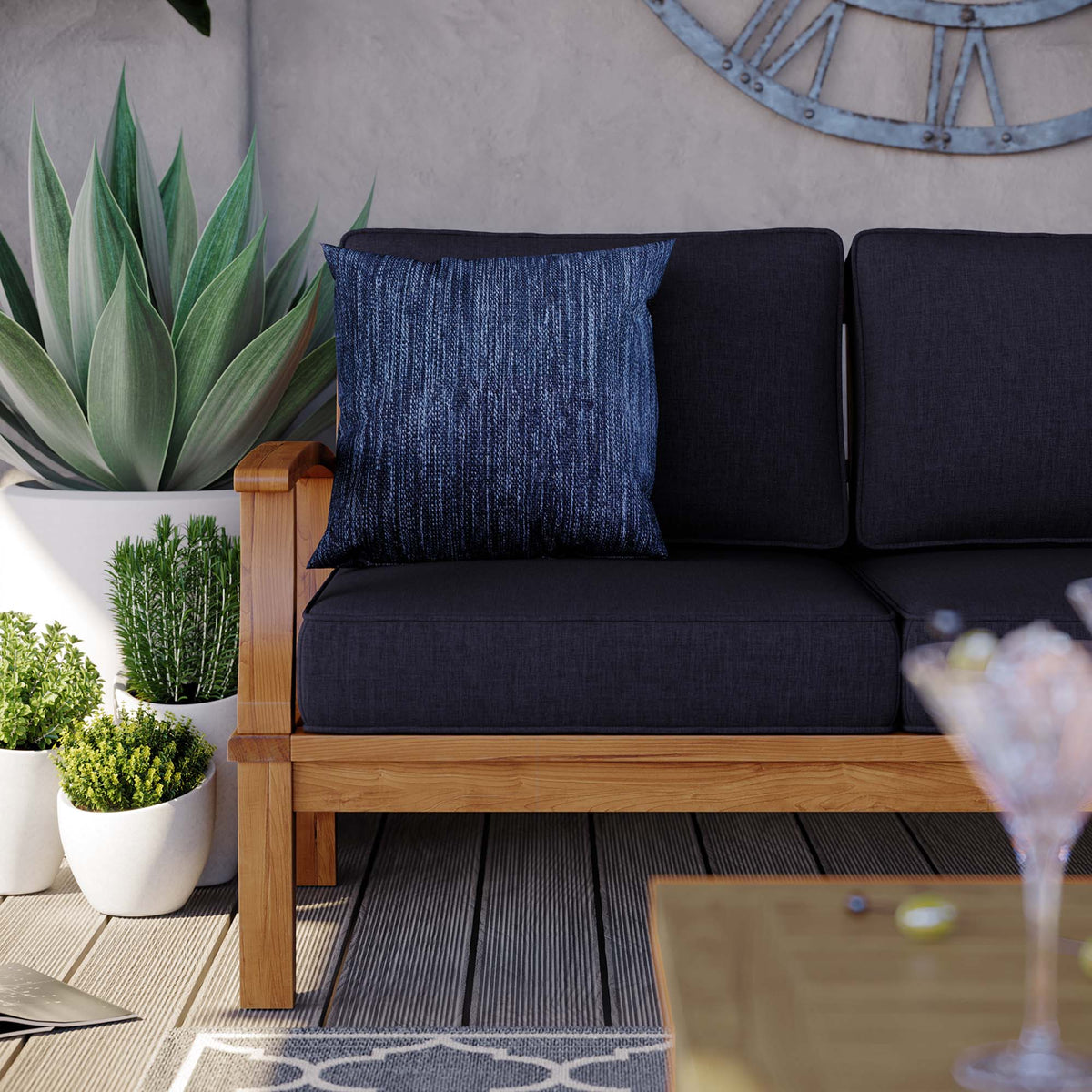 Marina Outdoor Patio Teak Sofa with dark cushions and a blue textured pillow on teak frame on Tampa Home & Garden Store