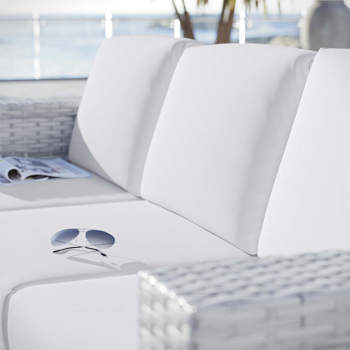 Convene outdoor patio sofa with white cushions and wicker base; sunglasses on table nearby on Tampa Home & Garden Store