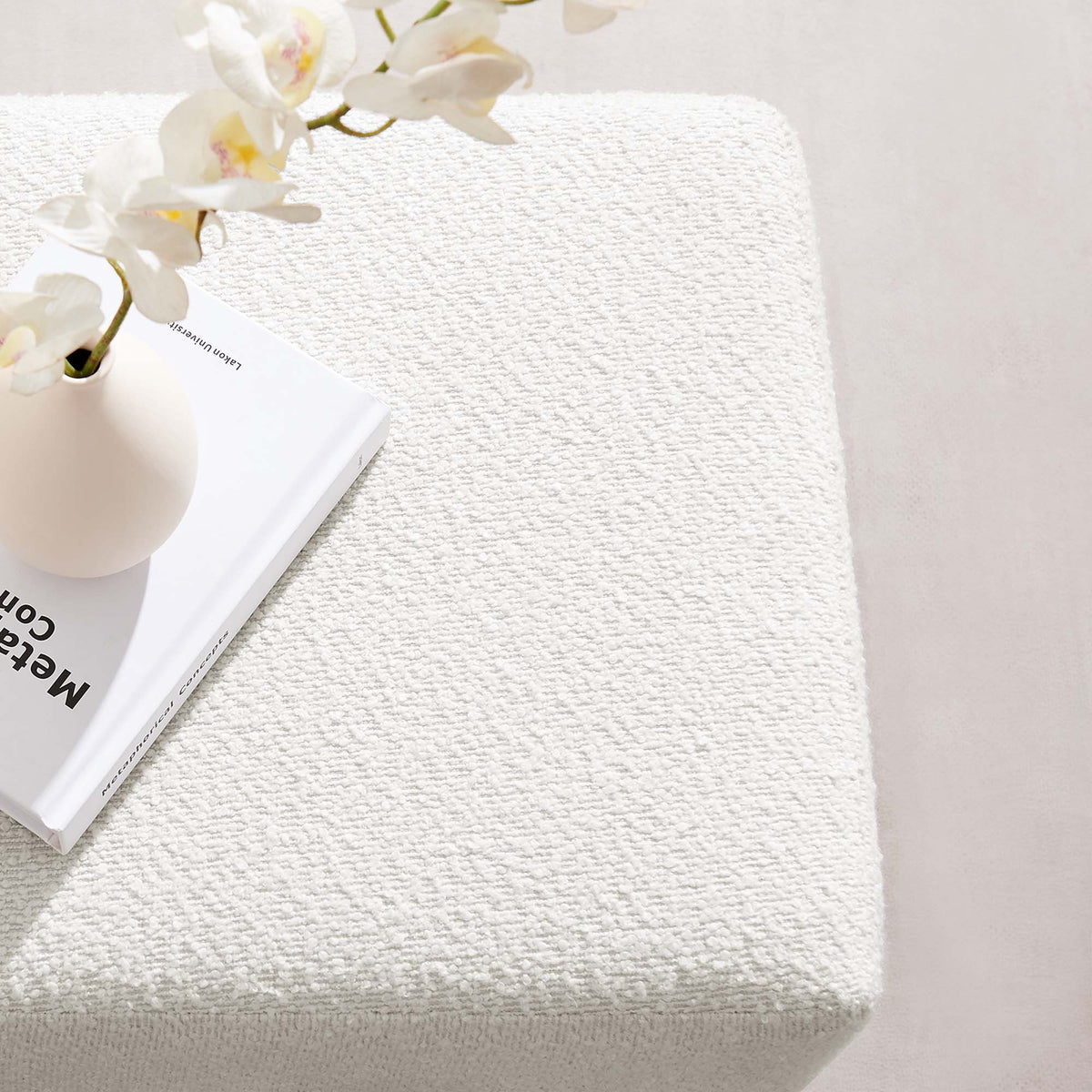 Tilden 17in square boucle ottoman in white fabric on textured rug with orchid vase on Tampa Home & Garden Store
