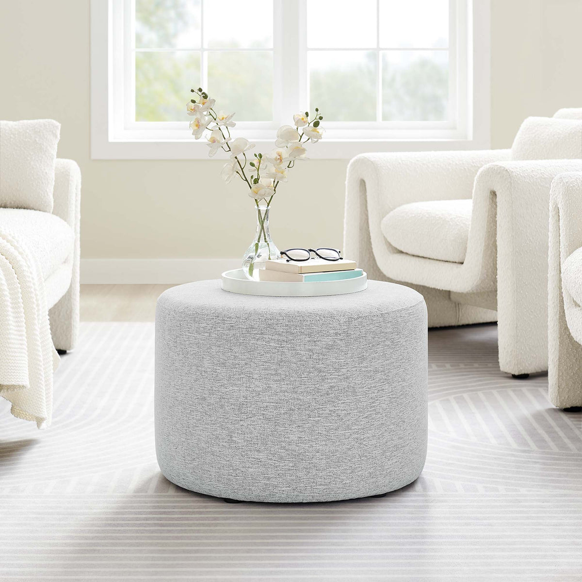 Callum round woven heathered fabric ottoman, light gray, orchid vase and books in a living room on Tampa Home & Garden Store