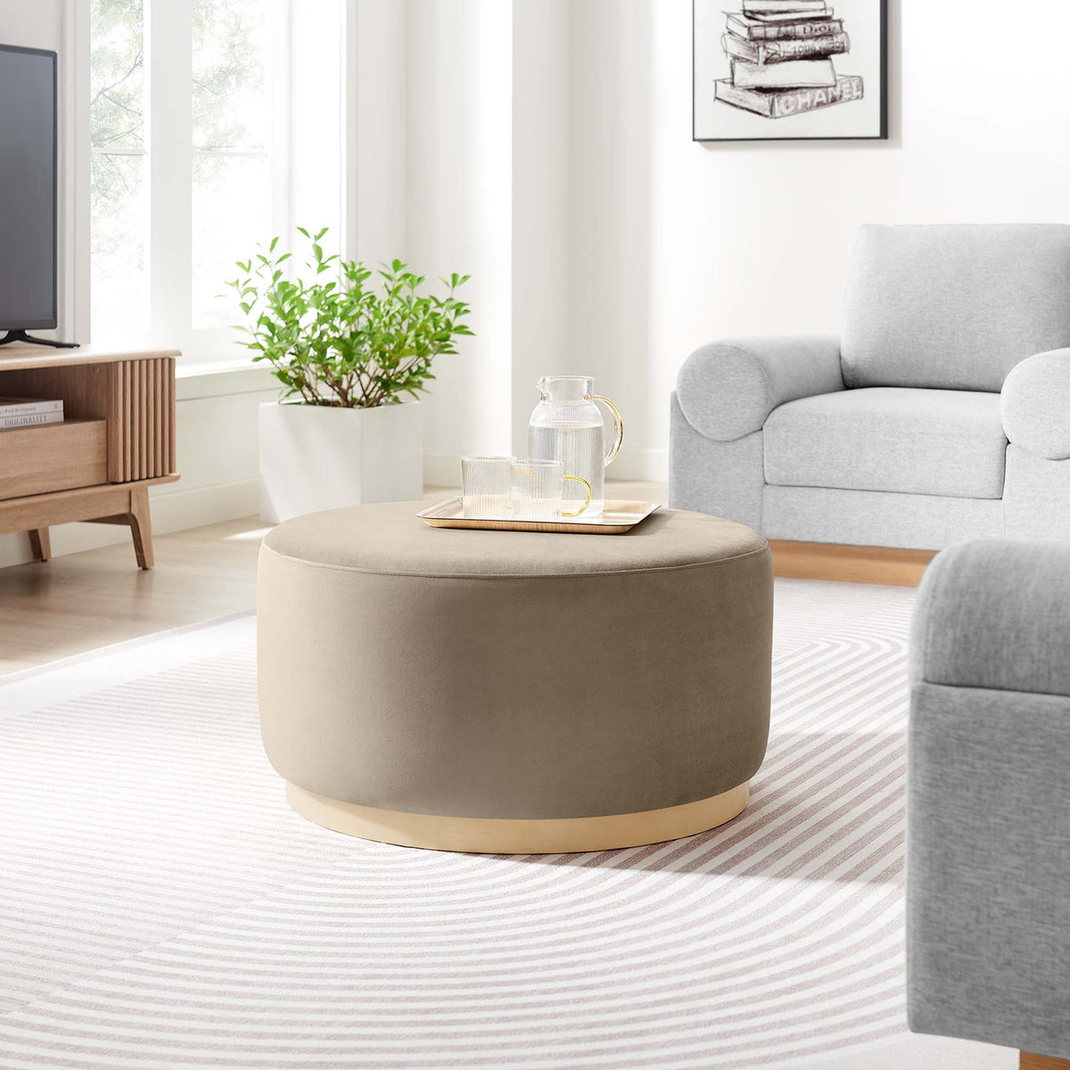 Tilden round velvet upholstered ottoman taupe with brass base in living room on Tampa Home & Garden Store