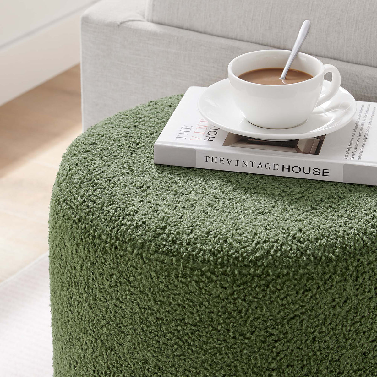 Tilden 16in round sherpa ottoman in green fabric; white coffee cup atop a magazine on Tampa Home & Garden Store