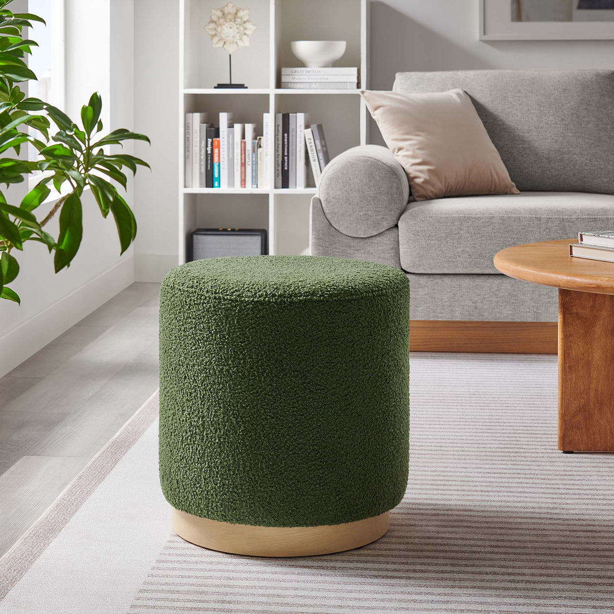 Tilden 16in round Sherpa ottoman in green fabric with natural wood base beside gray sofa and white bookshelf on Tampa Home & Garden Store