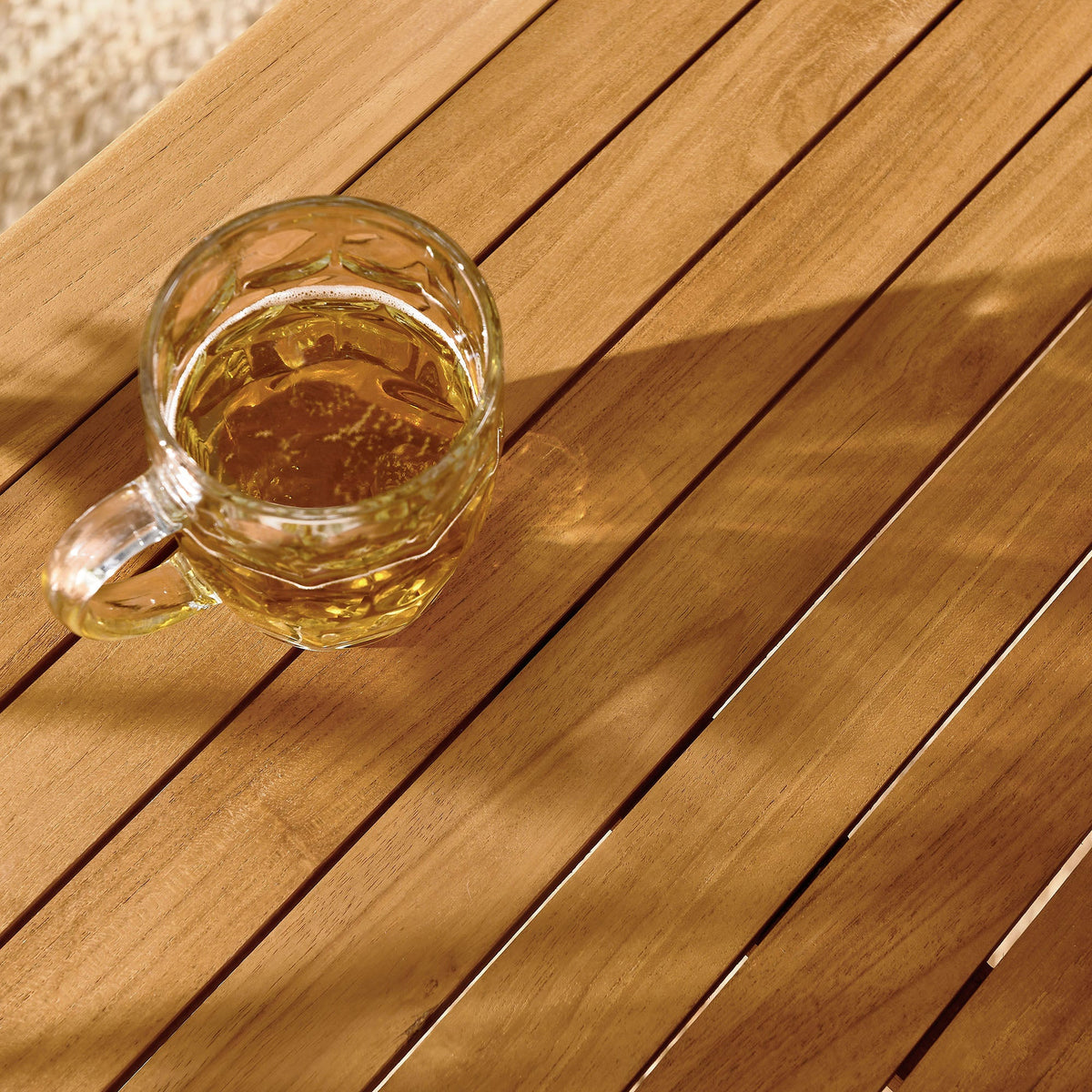 Vienna 34in square outdoor teak dining table with glass of beer on top on Tampa Home & Garden Store