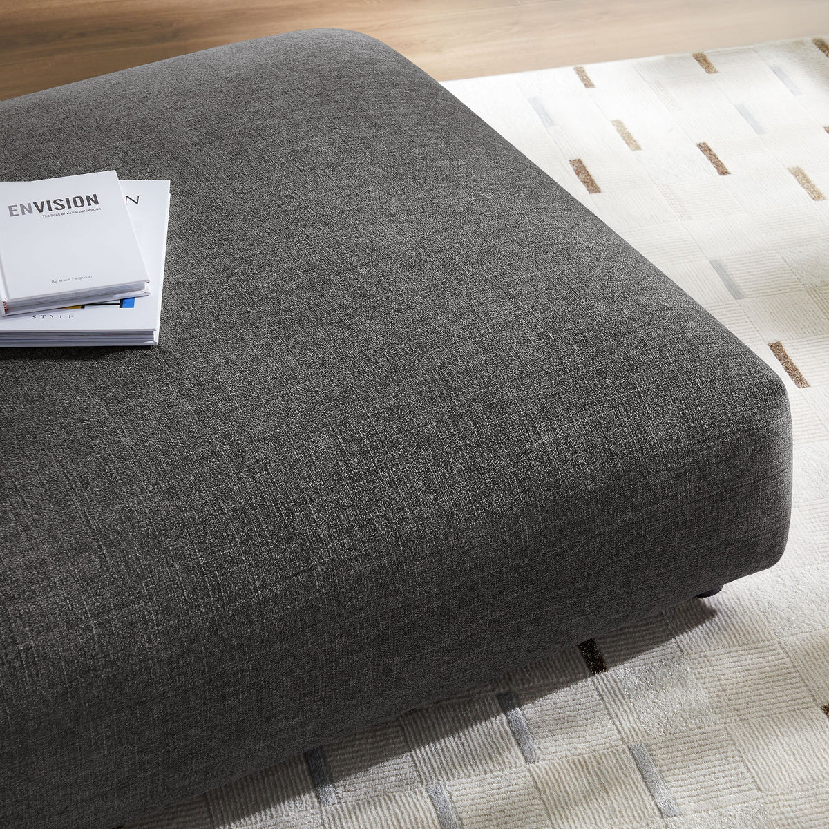 Solace modular upholstered fabric ottoman in dark gray with a magazine stack on Tampa Home & Garden Store