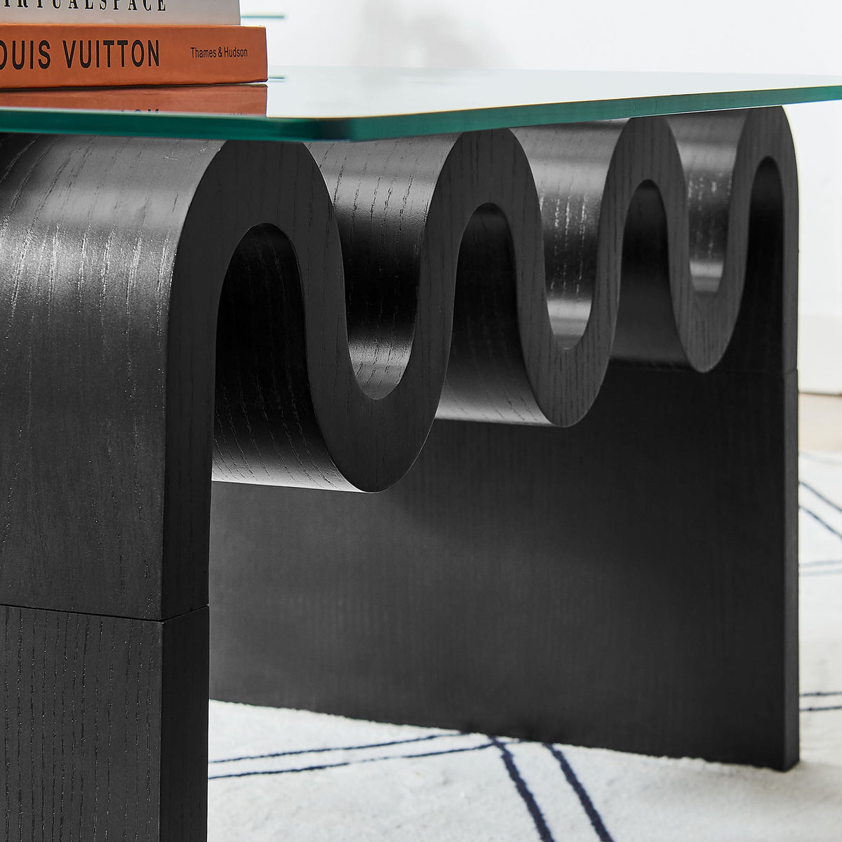 Ondine glass top coffee table with a black sculptural base featuring circular cutouts on Tampa Home & Garden Store