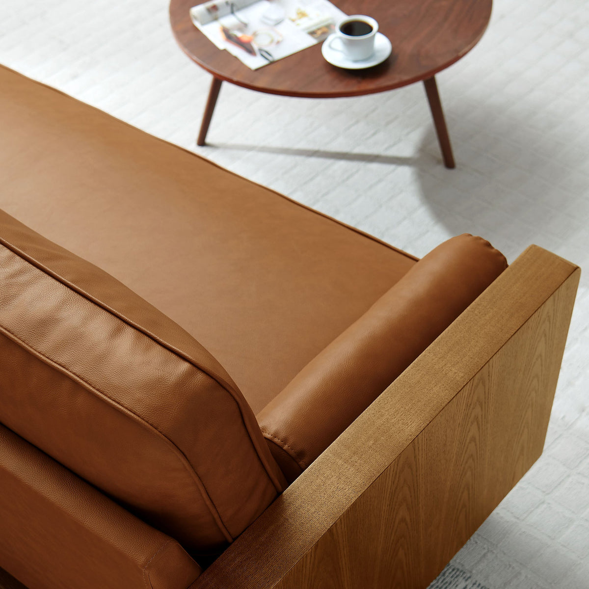 Kellan vegan leather sofa in brown with round wooden coffee table, cup and magazine on Tampa Home & Garden Store