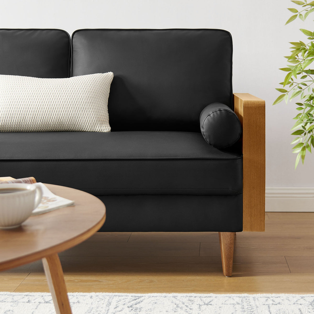 Kellan vegan leather loveseat in black with wood armrest and textured cushion in a living space on Tampa Home & Garden Store