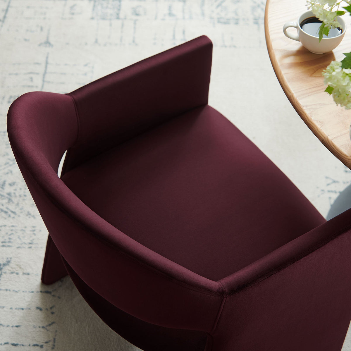 Talia Velvet Dining Armchair burgundy upholstery with curved arms beside a wood table on Tampa Home & Garden Store