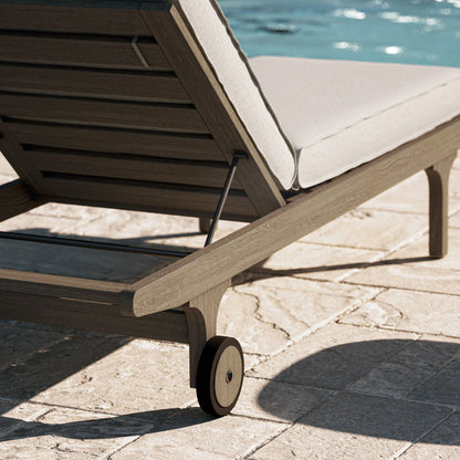 Saratoga teak outdoor chaise lounge chair with beige cushion and wheels by poolside on Tampa Home & Garden Store
