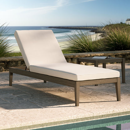 Northlake outdoor teak chaise lounge with beige cushion on a stone patio by the sea on Tampa Home & Garden Store