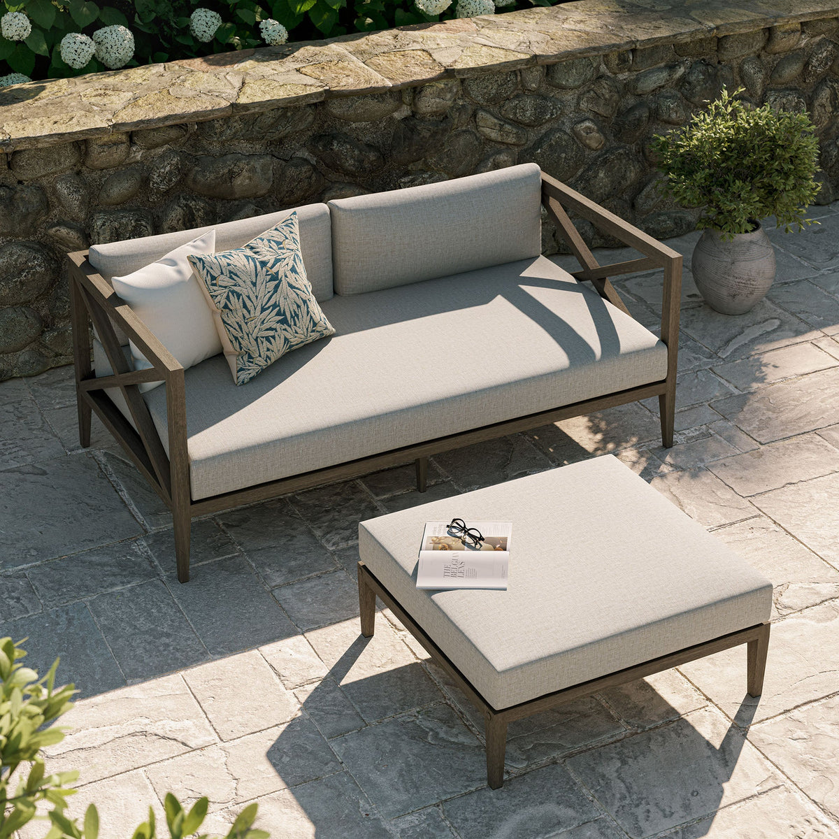 Northlake teak wood loveseat and ottoman with beige cushions on stone patio on Tampa Home & Garden Store