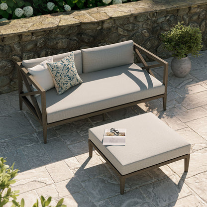 Northlake teak wood loveseat and ottoman with beige cushions on stone patio on Tampa Home & Garden Store