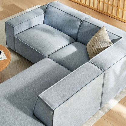 Modular L-shaped sectional sofa in light blue denim fabric with beige pillow on wood floor on Tampa Home & Garden Store