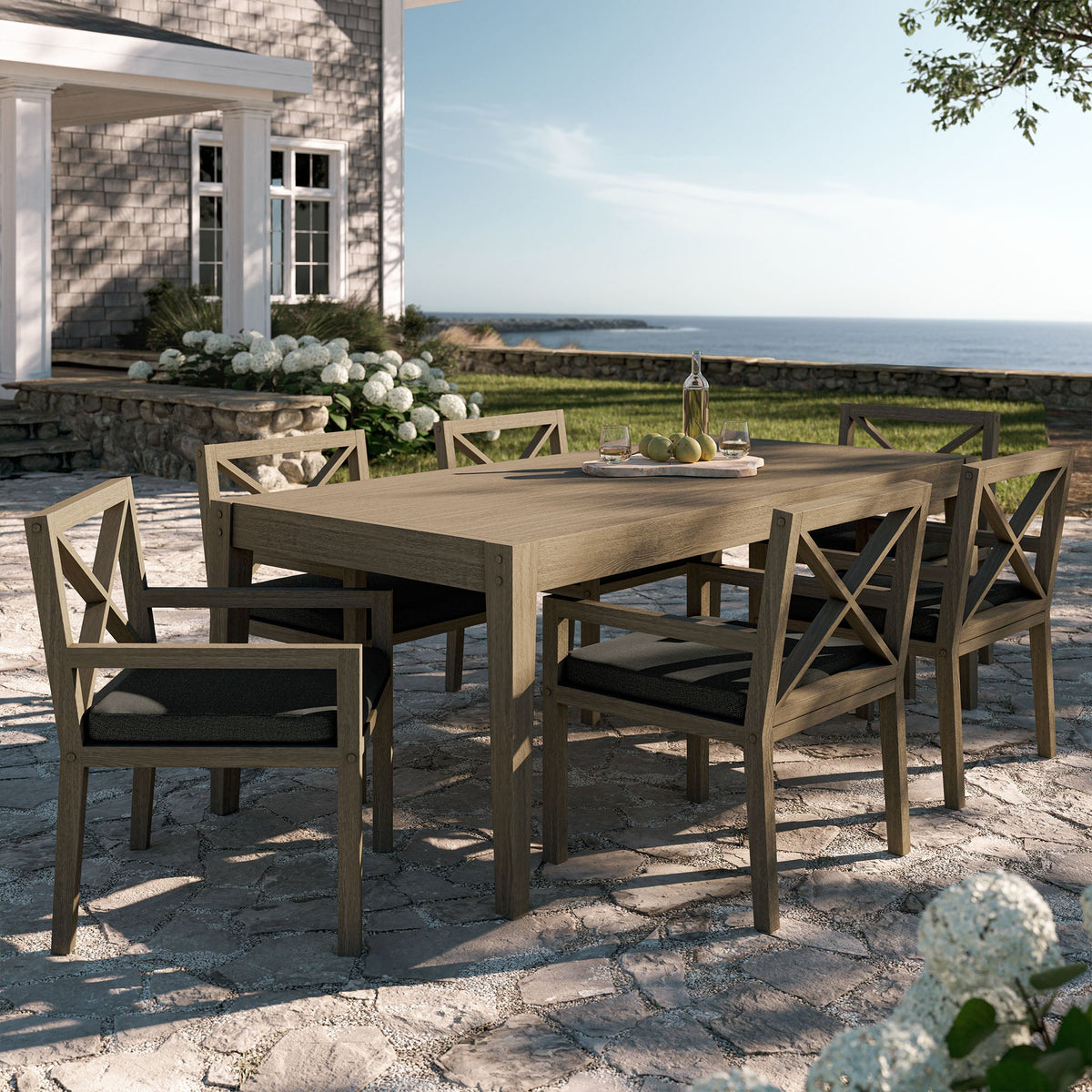 Northlake 7-piece teak outdoor dining set with cross-back chairs and cushions on sunlit patio on Tampa Home & Garden Store