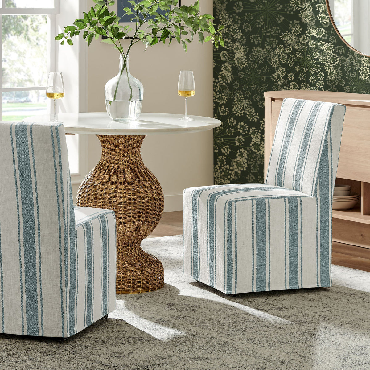 Tessera striped slipcovered dining side chairs in blue-gray fabric around a round white table on Tampa Home & Garden Store