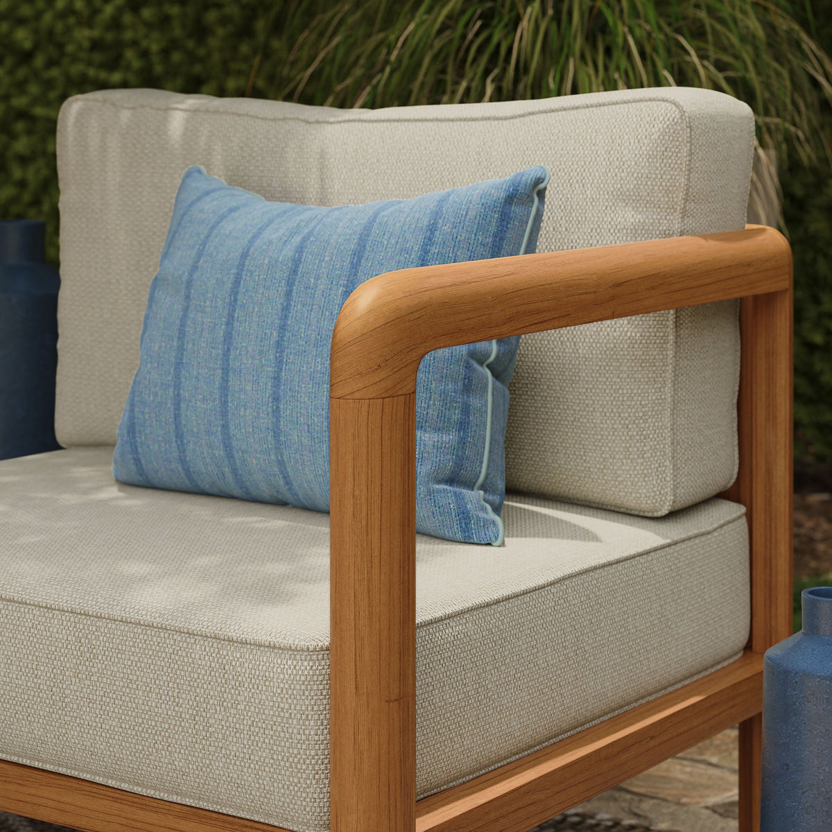 Kona outdoor teak right-arm facing modular armchair with beige woven cushions and a blue pillow on Tampa Home & Garden Store
