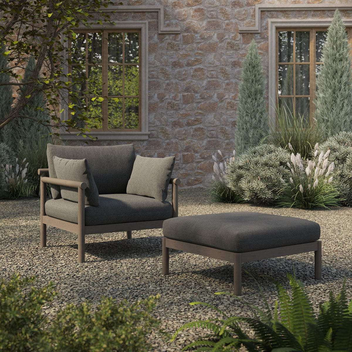 Eleni 2-Piece outdoor teak wood armchair and ottoman set with charcoal cushions on a stone patio on Tampa Home & Garden Store