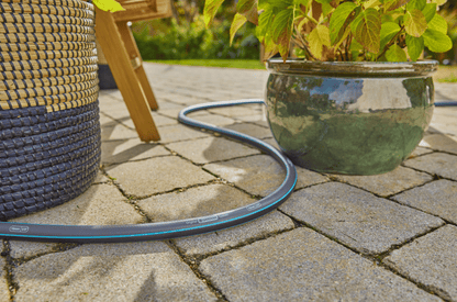 Gardena 30m/100ft garden hose 5/8 X-Flow coil on stone patio beside wicker furniture on Tampa Home & Garden Store