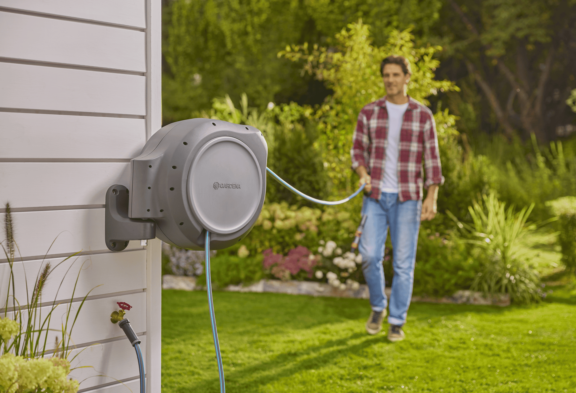 Retractable Hose Reel RollUp 50 ft by Gardena, retracting wall-mounted grey unit with blue hose on Tampa Home & Garden Store