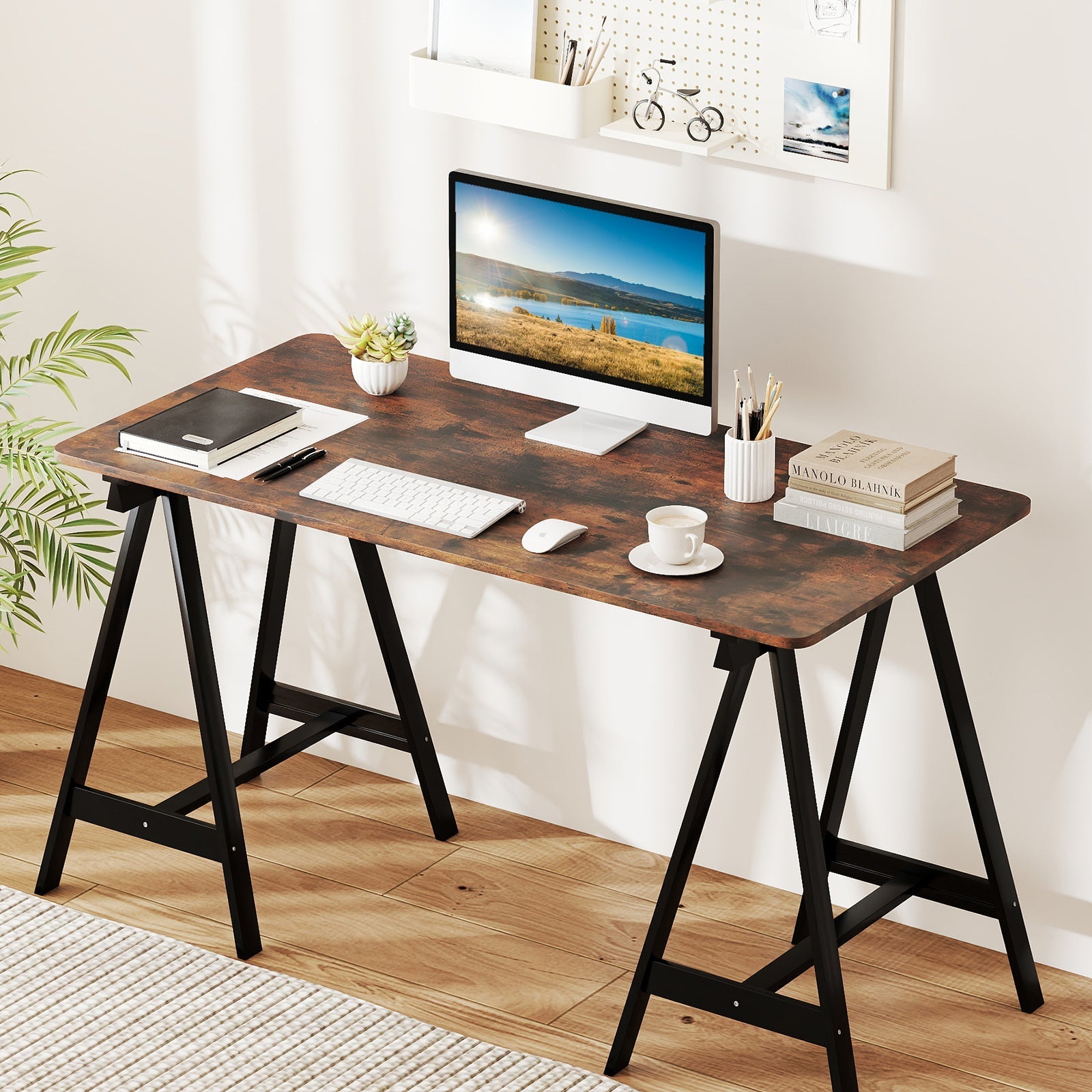 Rustic wood computer desk with black trestle legs, 27-inch monitor, keyboard, plant, mug, books on Tampa Home & Garden Store