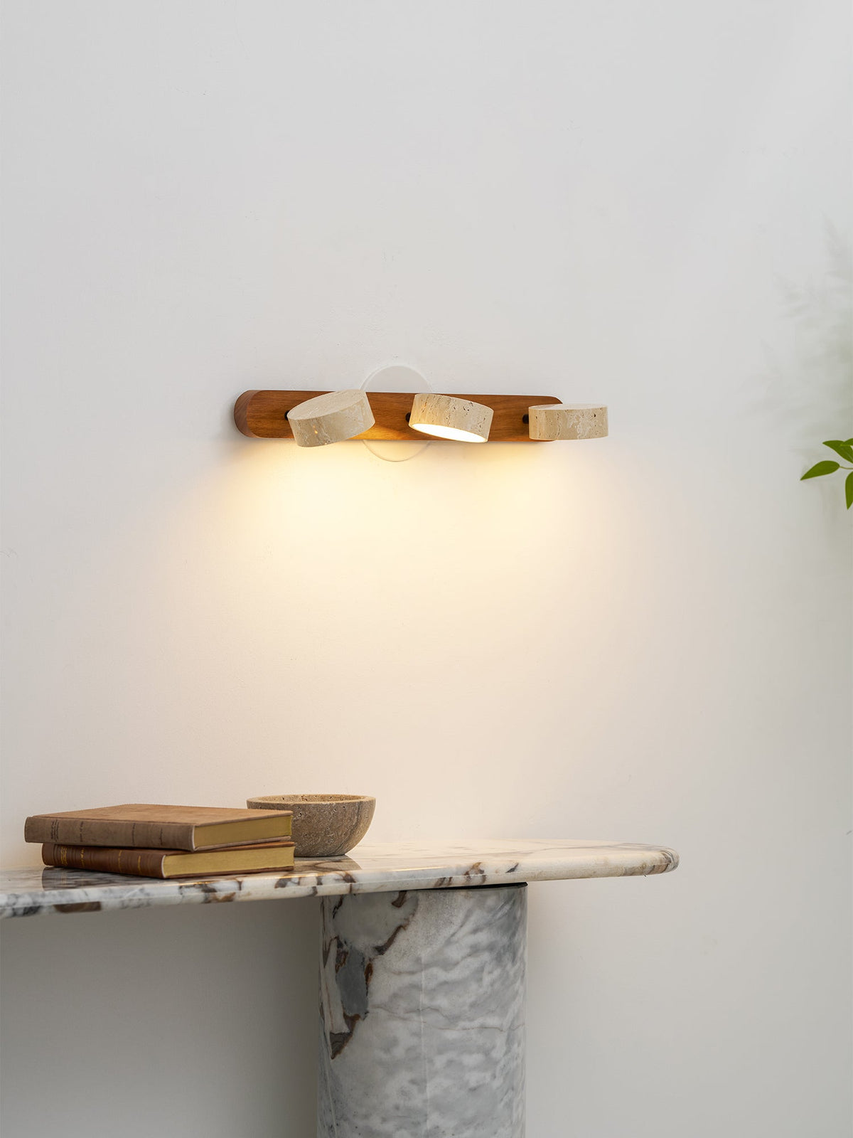 Moktan Sabai travertine stone wall sconce on natural wood bar with three LED heads, warm glow on Tampa Home & Garden Store