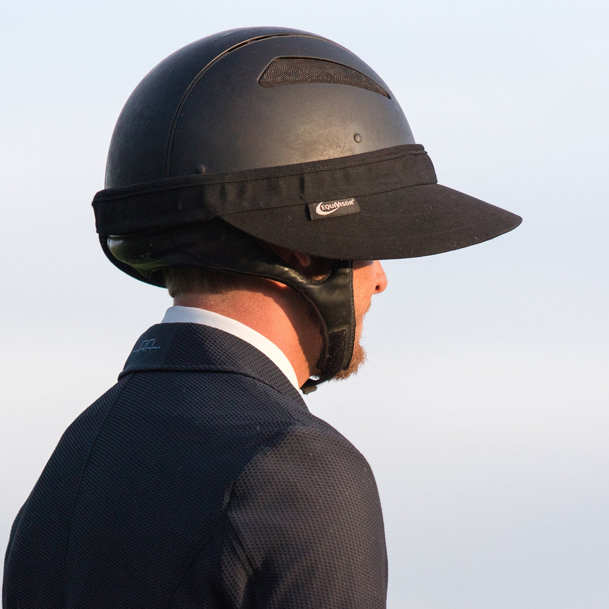 EquiVisor Original Shorty 3 sun visor on black riding helmet worn by a rider in a dark jacket on Tampa Home & Garden Store