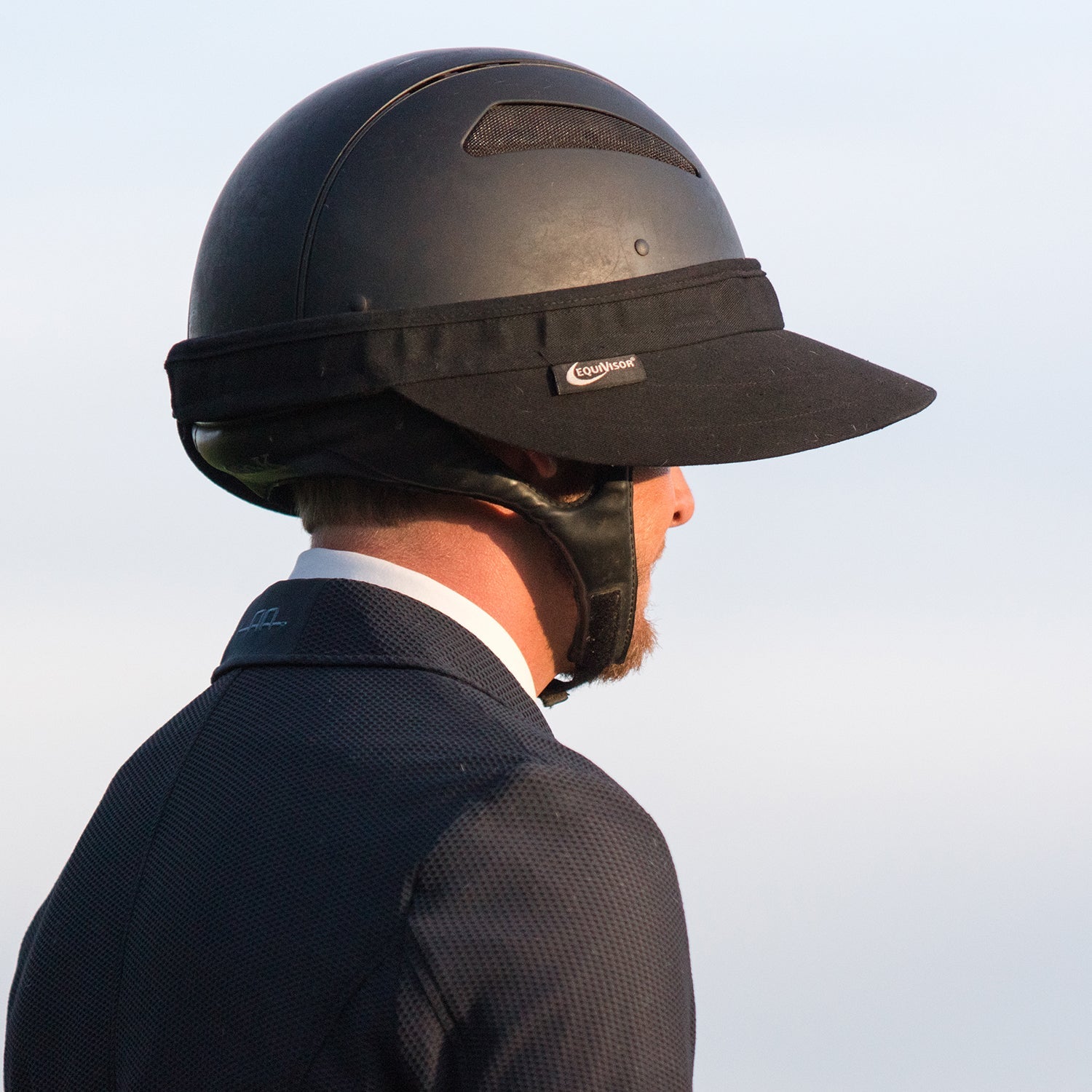 EquiVisor Original Shorty 3 sun visor on black riding helmet worn by a rider in a dark jacket on Tampa Home & Garden Store