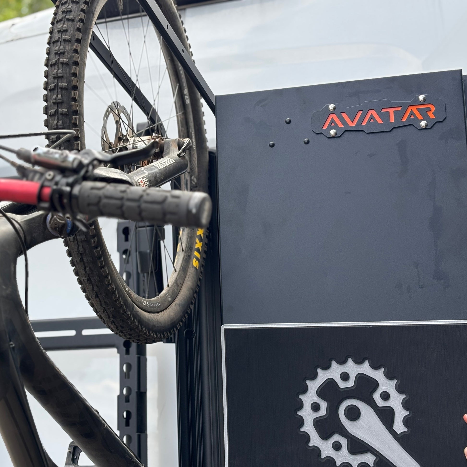Avatar Centi Van Storage Box in dark gray metal with Avatar logo, mounted on a bike rack on Tampa Home & Garden Store