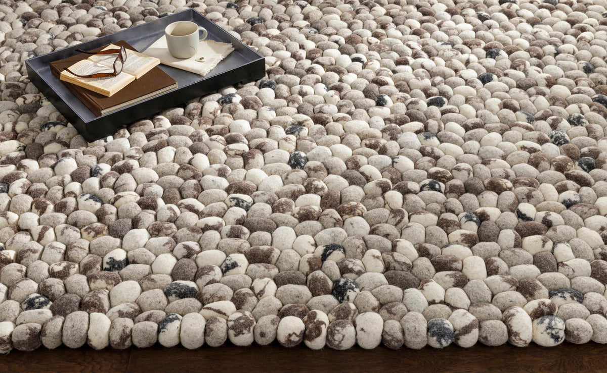 Fillmore Area Carpet by Boutique Rugs, pebble-textured rug in beige, with a tray of books on Tampa Home & Garden Store