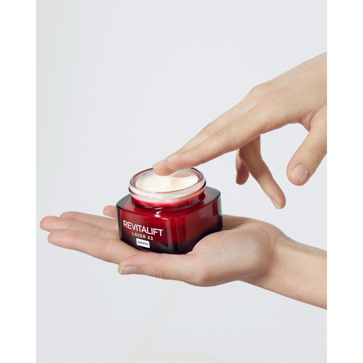 Revitalift Lazer X3 anti-aging day cream jar, red container with white cream, held by hands on Tampa Home & Garden Store