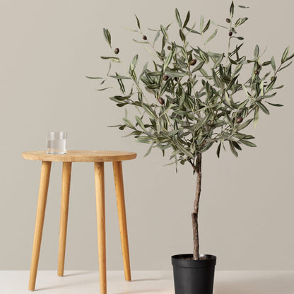 Faux Olive Tree in a black pot with olive-green leaves beside a wooden stool on Tampa Home & Garden Store