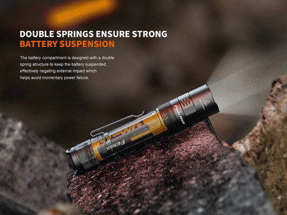 Fenix PD32R rechargeable LED tactical flashlight with silent switch resting on a rock on Tampa Home & Garden Store