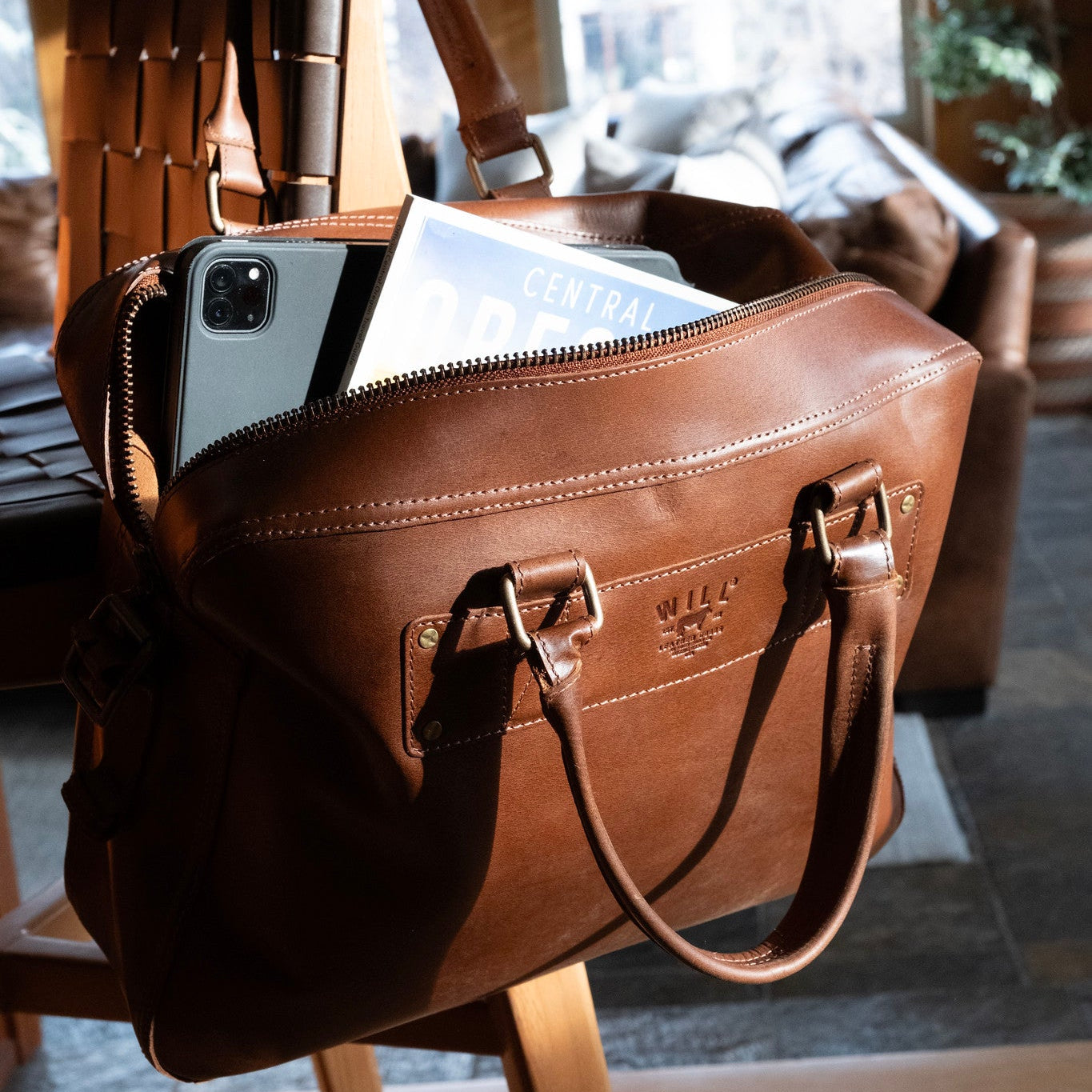 The Field Briefcase brown leather bag by Will Leather Goods holding phone and magazine on Tampa Home & Garden Store