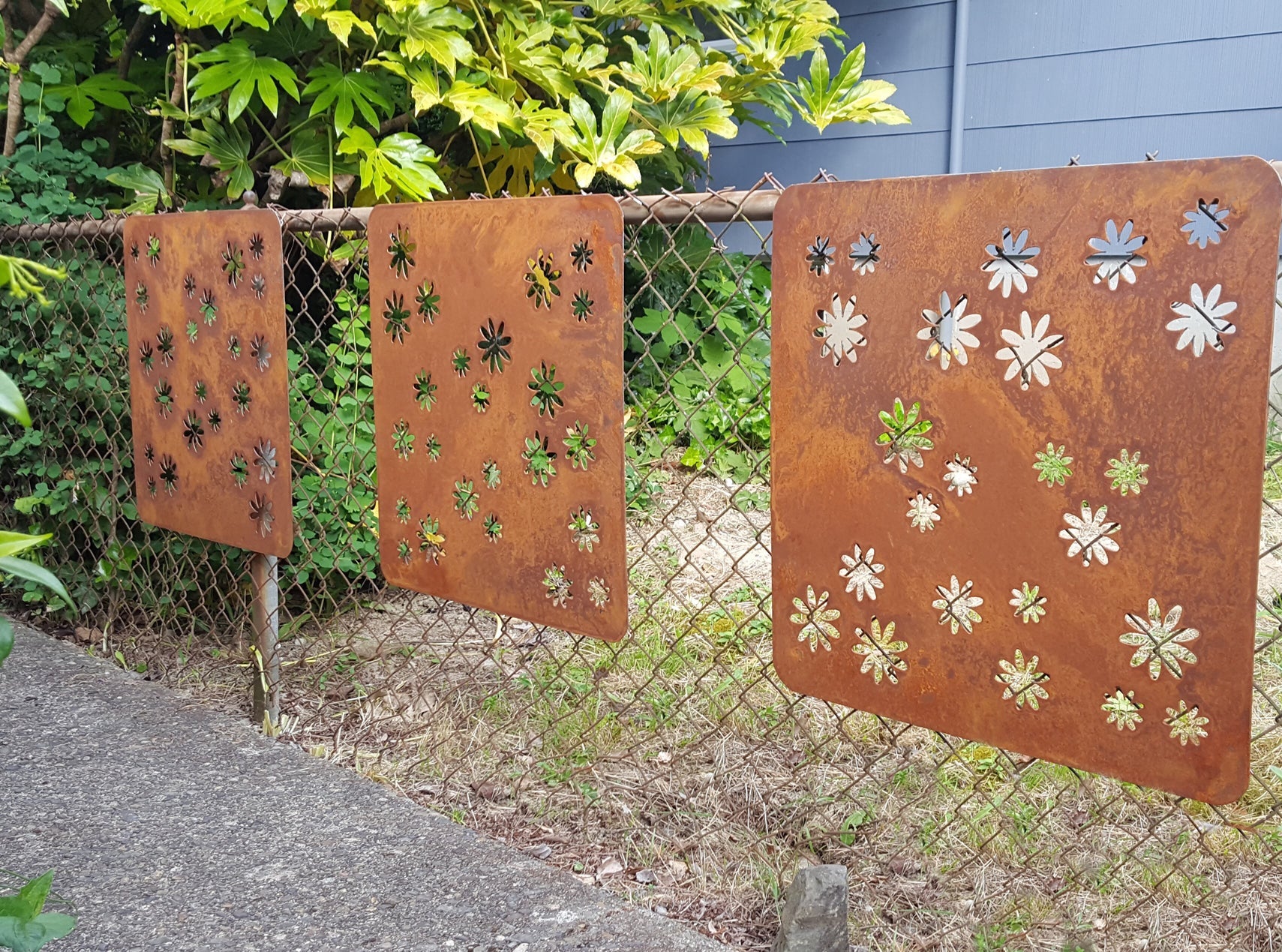Rust-colored metal privacy screens with flower cutouts; 3-panel set by Rustica Ornamentals on Tampa Home & Garden Store