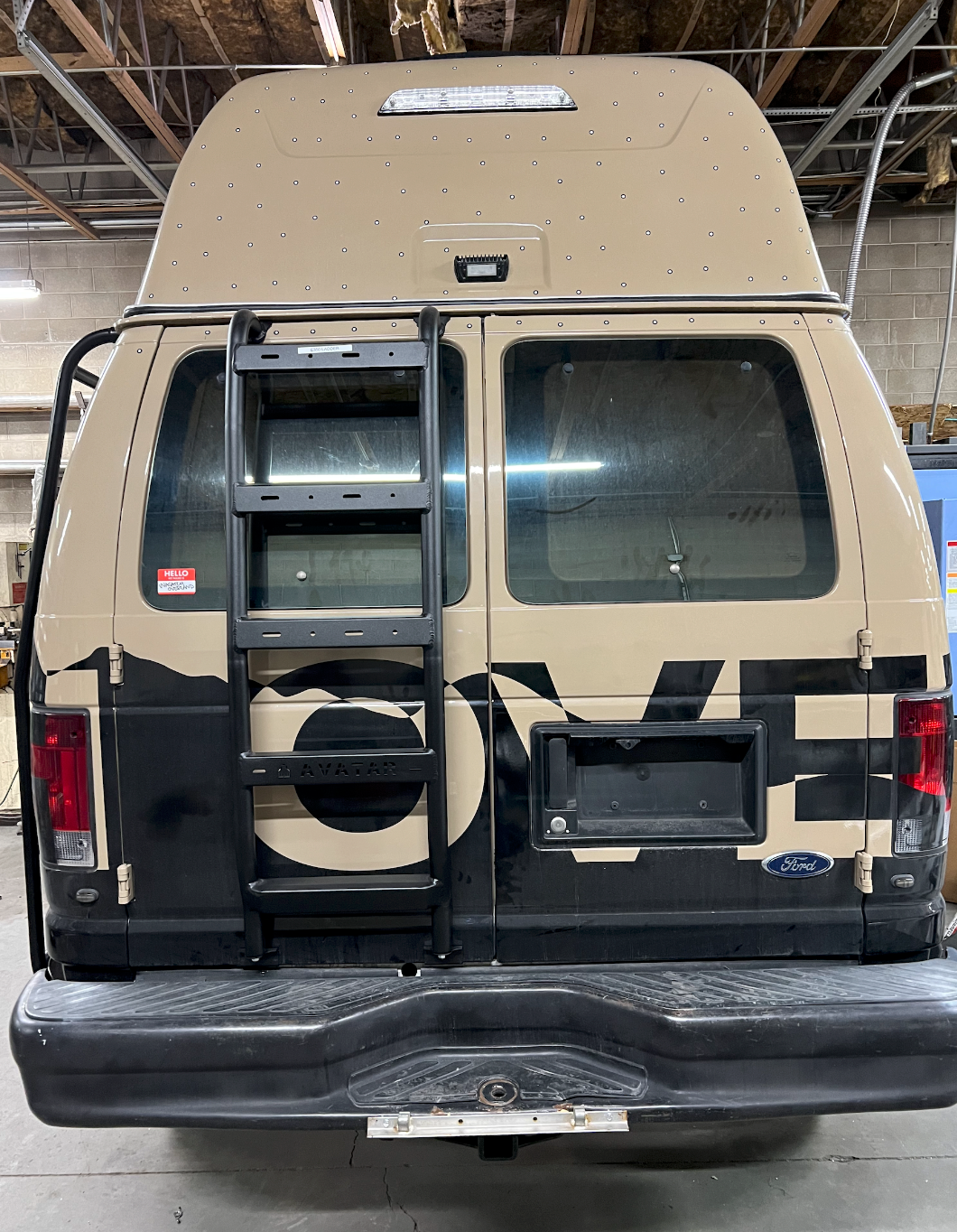 Ford E-Series rear ladder by avatar offroad, black steel ladder mounted on tan high-roof van rear on Tampa Home & Garden Store
