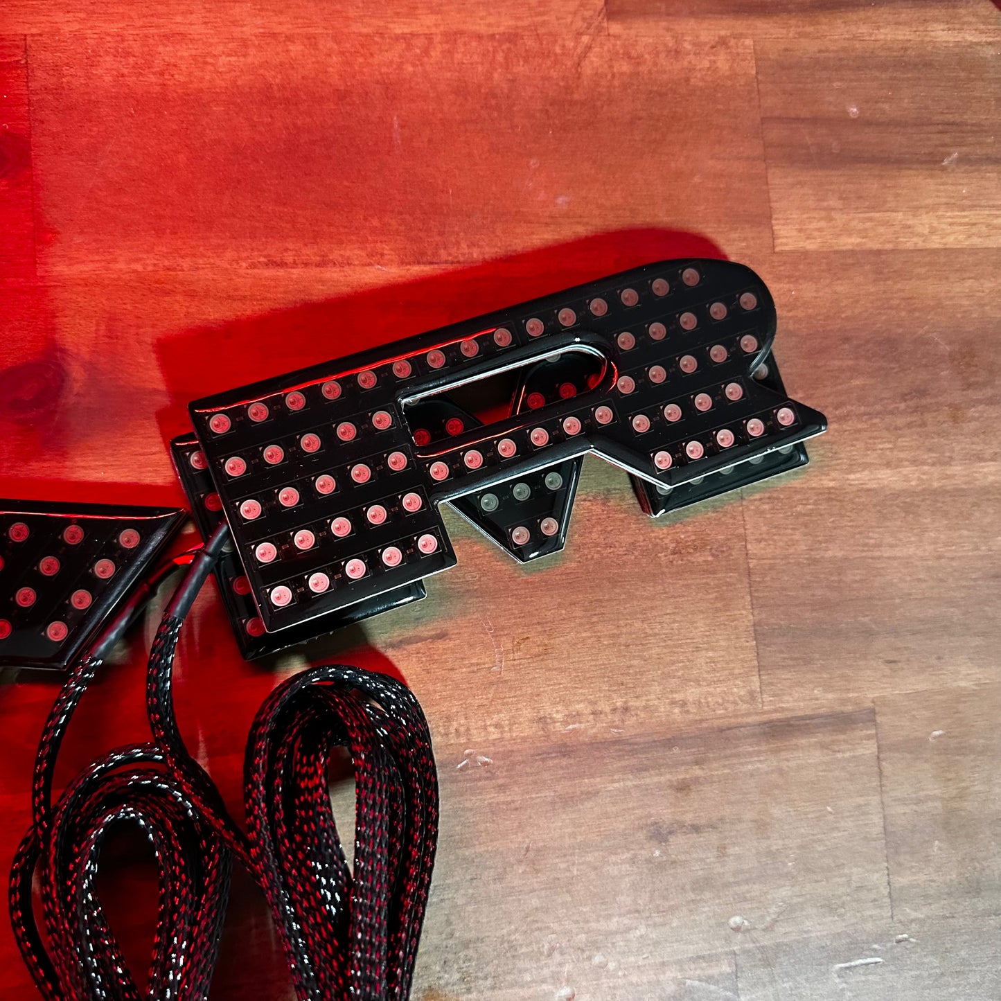 RAM RGBW Flow LED badge emblems in black housing with red glow for interior exterior use on Tampa Home & Garden Store