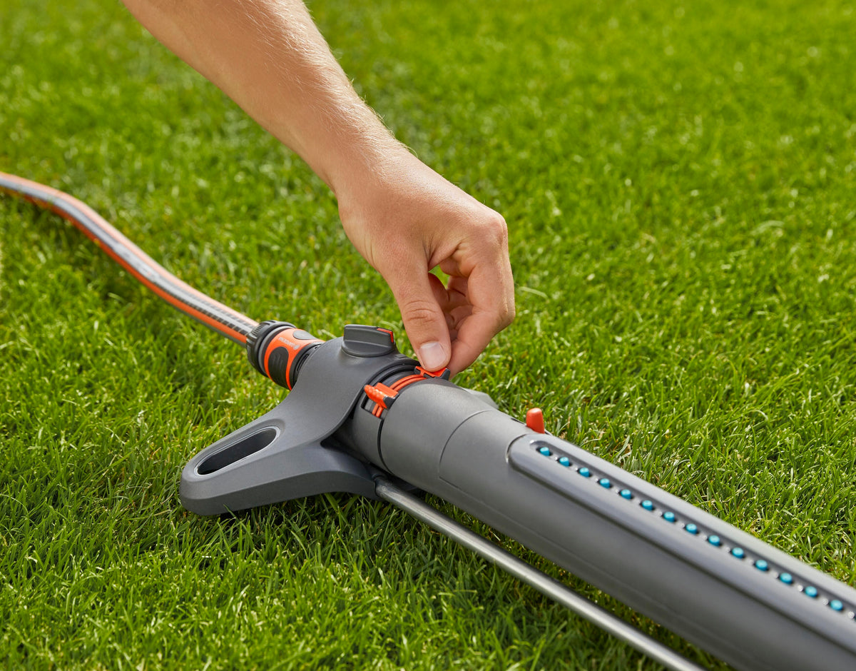 AquaZoom Oscillating Sprinkler Gardena on gray body with orange hose over green lawn on Tampa Home & Garden Store