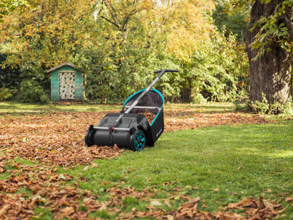 Leaf and Lawn Collector lawn sweeper by Gardena with black body, teal wheels, and silver handle in an autumn yard on Tampa Home & Garden Store