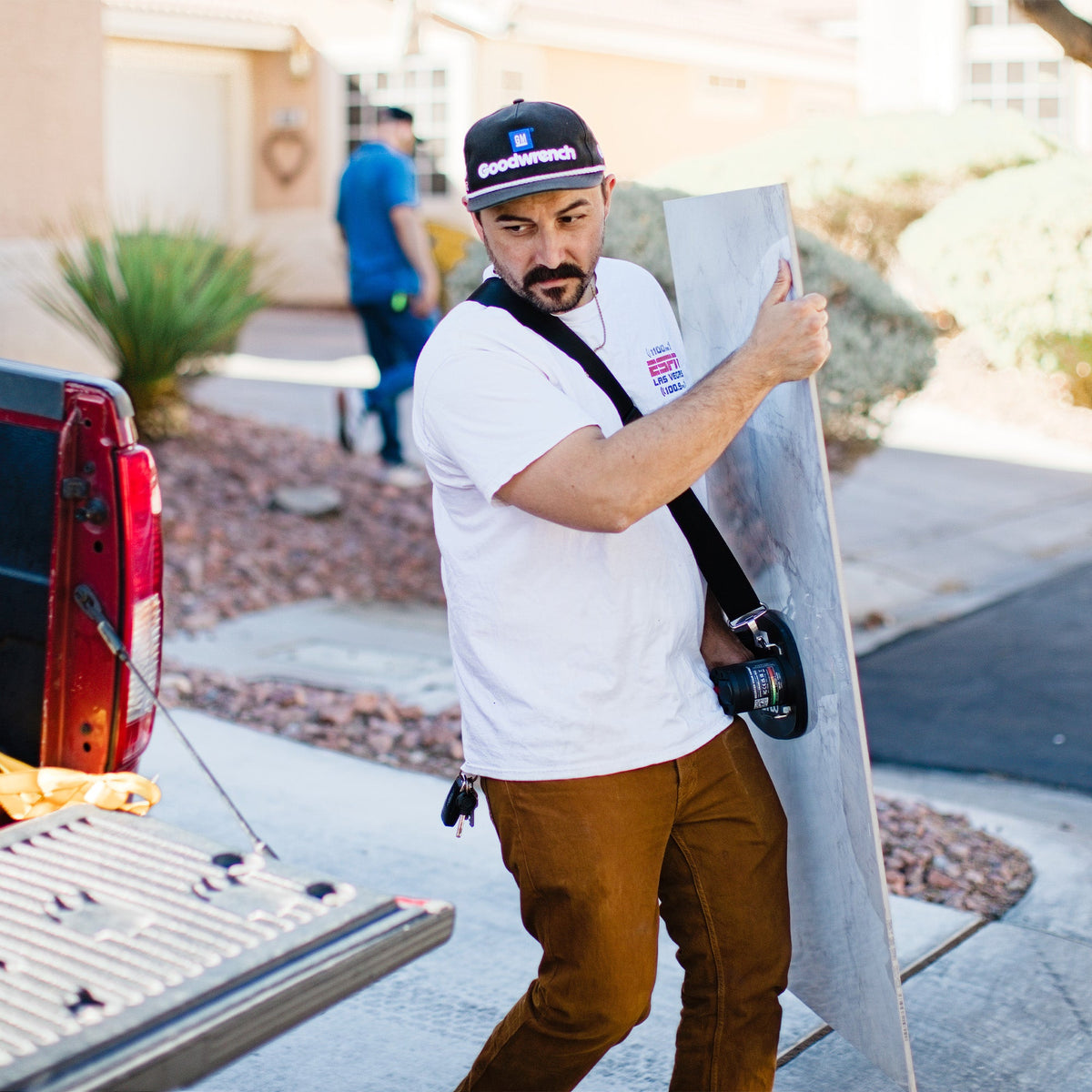 Lifting strap black GRIP TECH TOOLS securing a large board; man in white tee with a Goodwrench cap on Tampa Home & Garden Store