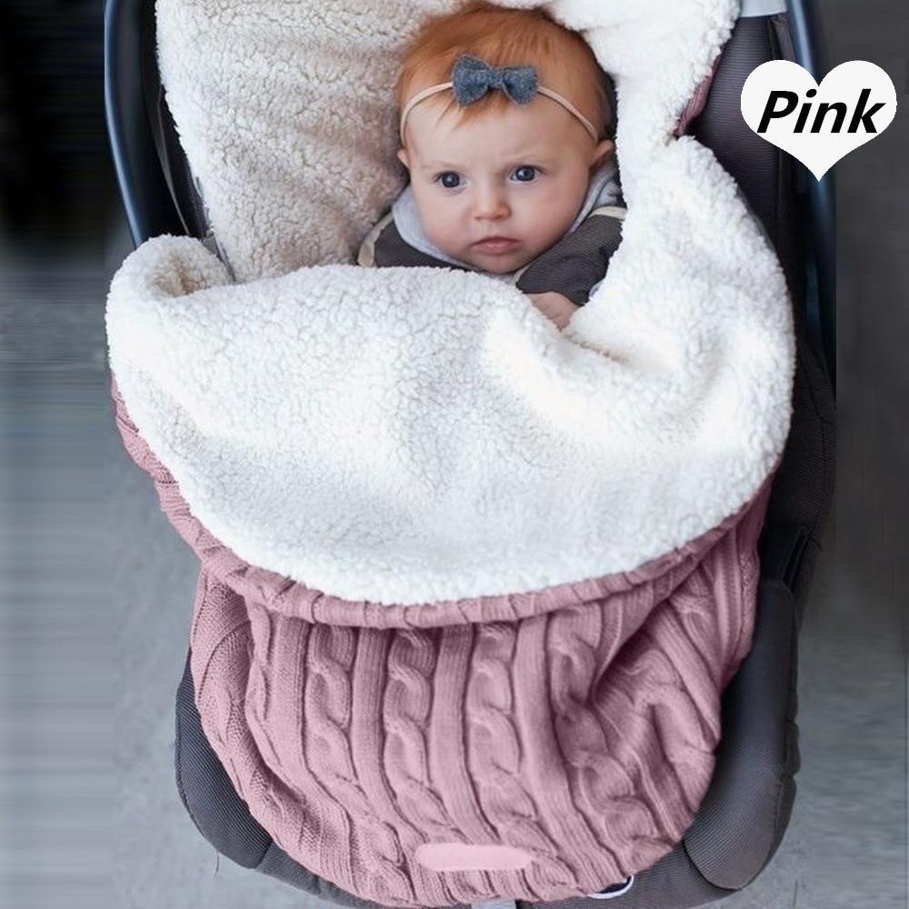 Stevvex pink knitted baby swaddle blanket with white lining in a stroller, baby wearing headband on Tampa Home & Garden Store